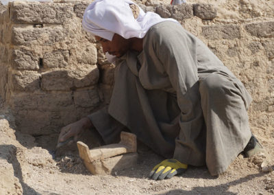 Haggag excava entre la capilla de adobe y un pequeño ataúd de barro para un shabti.