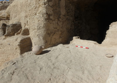 Entrada a la tumba asociada al jardín, con un plato y una vasija apoyados sobre un suelo de mortero.
