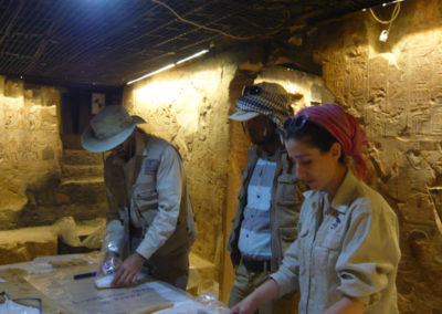 Curro, el inspector Ahmed y Gudelia revisan un conjunto de linos con inscripción.