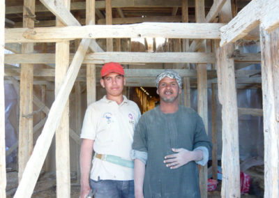 Yasín posa junto a uno de los encargados de montar el andamiaje para el encofrado del techo del nuevo cierre de la tumba de Djehuty.