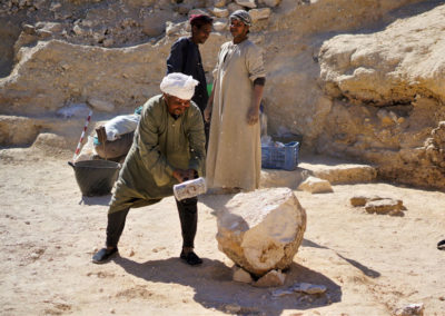 Yuma rompe a martillazos un gran bloque de piedra para poder retirarlo de la zona de excavación de Angie.