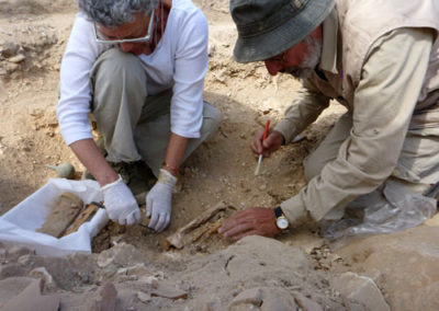 Pía y José Miguel excavan un modelo de ataúd de madera pintado, con inscripción.