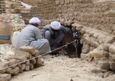 Sayed y Hamdi refuerzan la base del muro de adobe del patio de Djehuty.