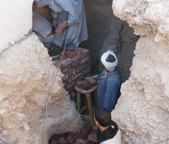 Alí y Sayed refuerzan la base del muro de adobe de Djehuty, a la entrada de la tumba de la dinastía XI.