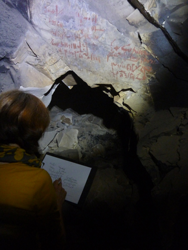 Tina colaciona un par de grafiti al final de la gran galería que se abre desde la capilla ramésida, por encima de las tumbas.