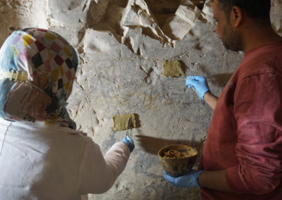 Esmá y Ahmed aplican arcilla bentonite para tratar de retirar las incrustaciones de barro de las paredes.