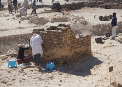 Fatima y Carmen consolidan la capilla de adobe junto a la excavación.