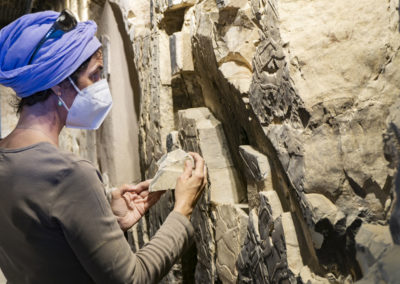 Lucía trata de colocar un fragmento de relieve en una de las paredes de la tumba de Djehuty.
