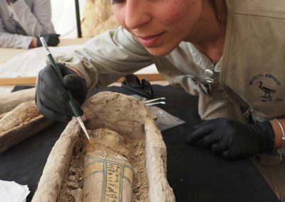 Laura excava el pequeño sarcófago de barro con el ataúd de madera dentro.