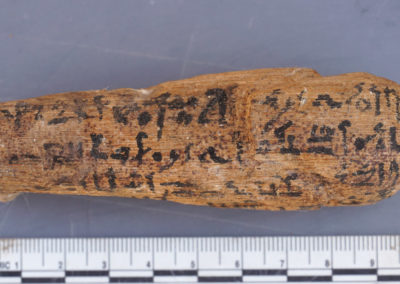Parte de atrás de un shabti de madera, con la fórmula del shabti escrito en líneas horizontales.